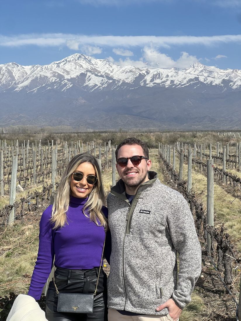 Paula e Francisco nos vinhedos de Mendoza, com a cordilheira nevada ao fundo